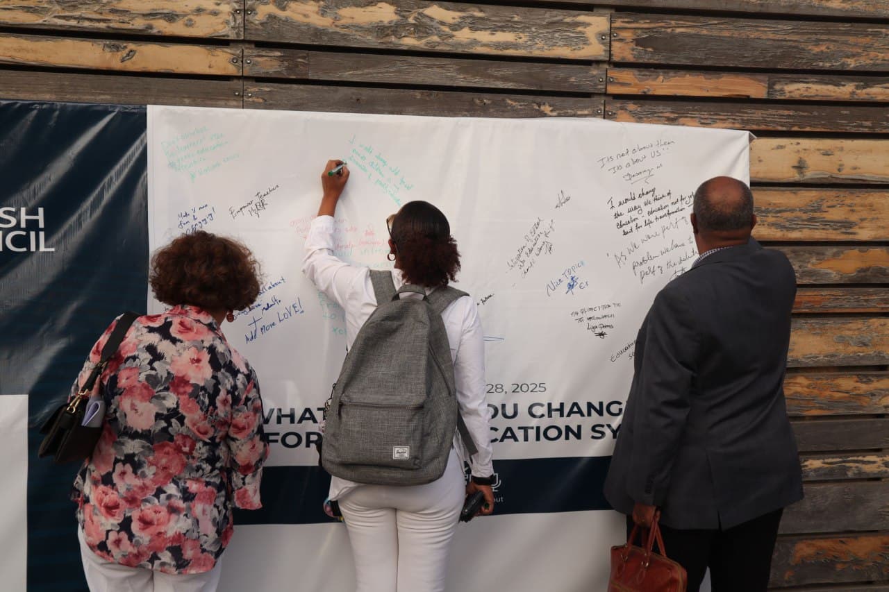 Attendees writing answers on a wall asking what they would change in the education system